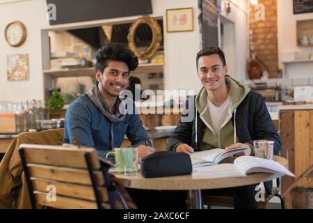 Portrait confident young male college students studying at cafe table Stock Photo