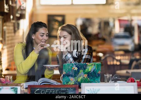 Young female college students studying, eating dessert at cafe window Stock Photo