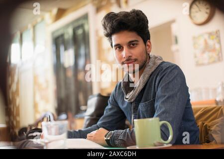 Portrait confident young male college student studying in cafe Stock Photo