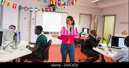 Community college instructor guiding adult students using computers in classroom Stock Photo