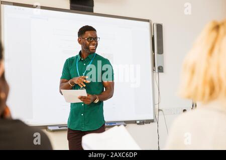 Male community college instructor leading lesson at projection screen in classroom Stock Photo