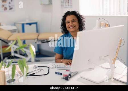 Portrait confident female doctor working at computer in doctors office Stock Photo