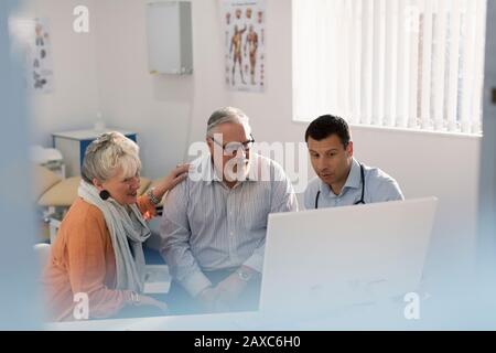 Doctor meeting with senior couple at computer in doctors office Stock Photo