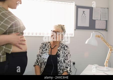 Female doctor talking with pregnant patient in doctors office Stock Photo