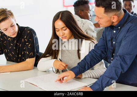 High school teacher helping students with homework in classroom Stock Photo
