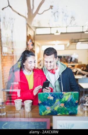 Young couple using smart phone at cafe window Stock Photo