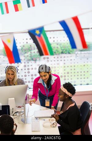 Female community college instructor helping student at computer in computer lab Stock Photo