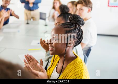 Smiling high school girl student clapping in classroom Stock Photo