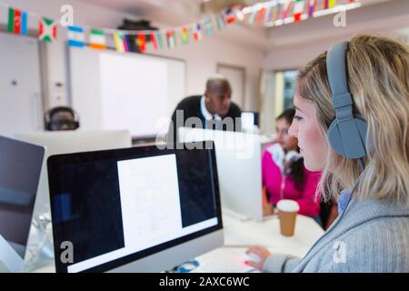 Female community college student with headphones using computer in computer lab classroom Stock Photo