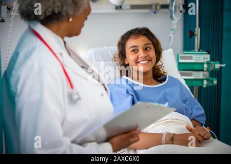 Smiling girl patient talking with doctor in hospital room Stock Photo
