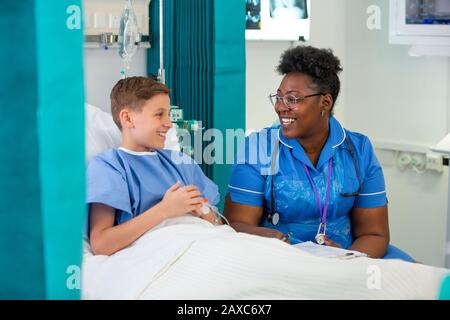 Female nurse talking with boy patient in hospital room Stock Photo