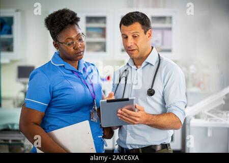 Male doctor with digital tablet talking with female nurse in hospital Stock Photo