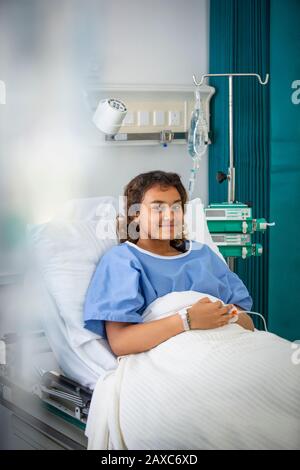 Portrait smiling girl patient in hospital bed Stock Photo