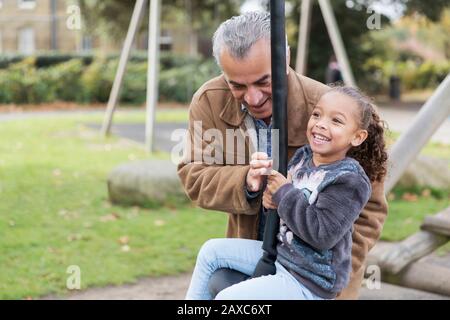 Happy grandfather and granddaughter playing at playground Stock Photo