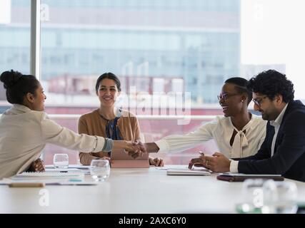 Businesswomen shaking hands in conference room meeting Stock Photo