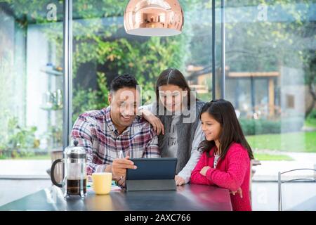Father and daughters using digital tablet at breakfast table Stock Photo
