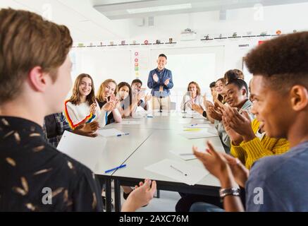 High school students and teacher clapping for student in debate class Stock Photo