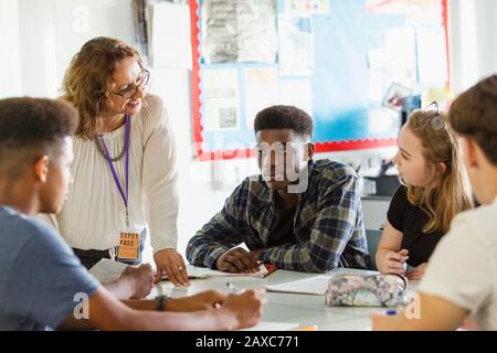 High school teacher talking with students at table in classroom Stock Photo