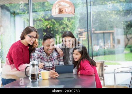 Happy family using digital tablet at kitchen table Stock Photo