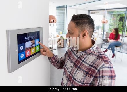 Man setting touch screen smart home alarm Stock Photo