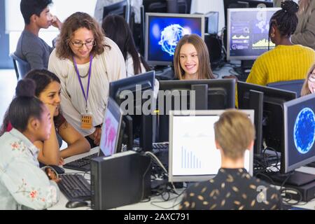 Junior high teacher helping students using computers in computer lab Stock Photo