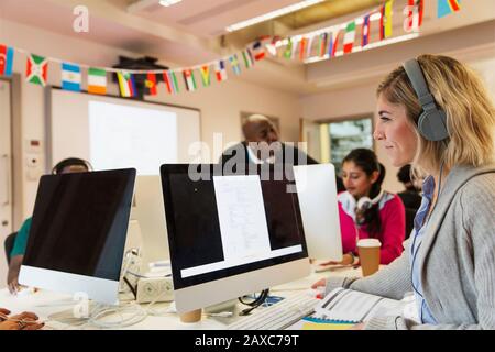 Female community college student with headphones using computer in computer lab classroom Stock Photo