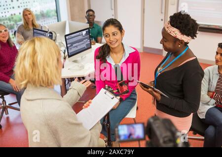 Community college journalism students at microphone in classroom Stock Photo