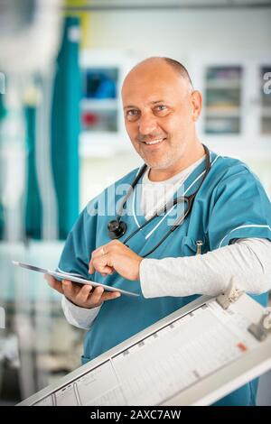 Portrait smiling, confident male doctor using digital tablet in hospital Stock Photo