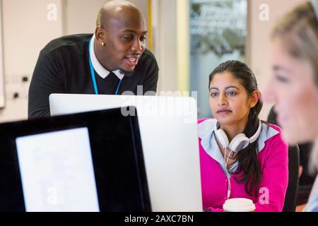 Community college instructor helping student at computer in classroom Stock Photo
