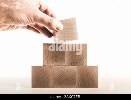 hand placing last wood block on top of pyramid, business growth concept Stock Photo