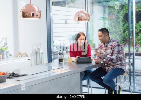 Couple using digital tablet at kitchen island Stock Photo