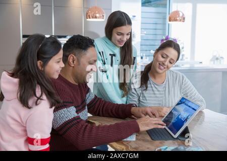 Family using digital tablet at kitchen table Stock Photo
