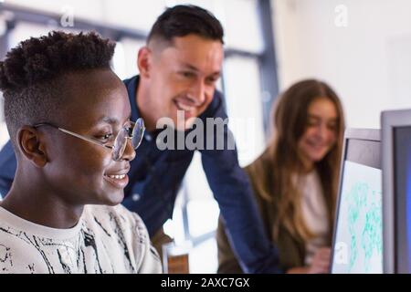 Junior high teacher helping students using computers in computer lab Stock Photo