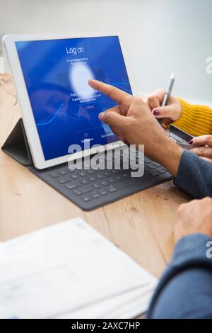 Couple paying bills, logging on to digital tablet with fingerprint Stock Photo