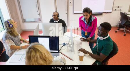 Community college instructor helping students at computers in computer lab classroom Stock Photo