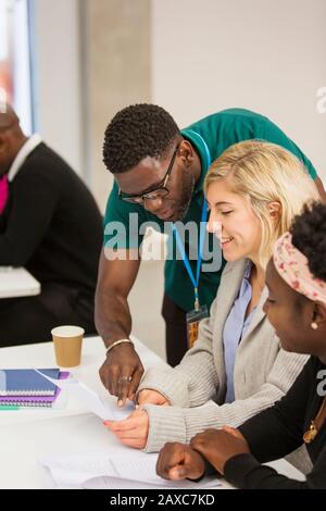 Community college instructor helping students with paperwork in classroom Stock Photo