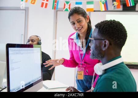 Community college instructor helping student at computer in classroom Stock Photo