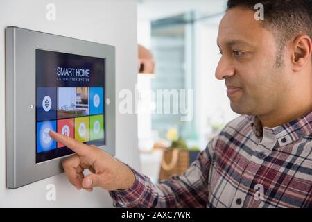 Man setting smart home navigation system alarm at touch screen Stock Photo
