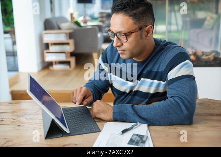 Focused man paying bills at digital tablet Stock Photo