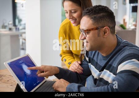 Couple using digital tablet, logging on with fingerprint Stock Photo