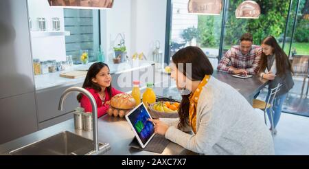 Family talking, using digital tablets in kitchen Stock Photo