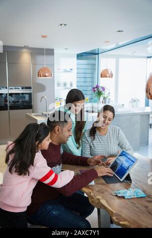 Happy family planning vacation at digital tablet at dining table Stock Photo