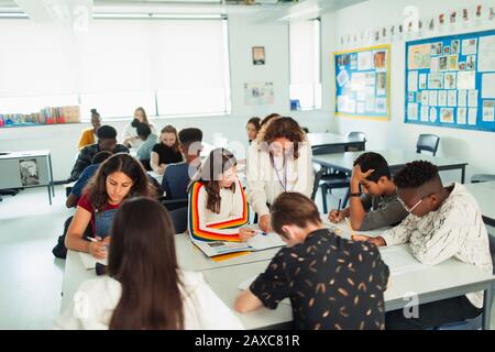 High school teacher helping students studying in classroom Stock Photo