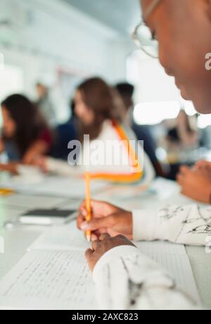 High school boy student taking notes, writing in notebook in classroom Stock Photo