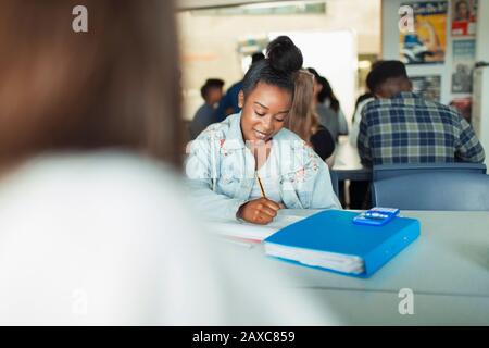 High school girl student doing homework at table in classroom Stock Photo