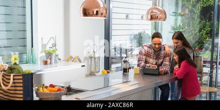 Father and daughters using digital tablet in morning kitchen Stock Photo