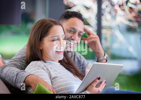 Happy couple relaxing, using digital tablet Stock Photo