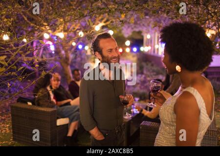 Friends talking and drinking at garden party Stock Photo