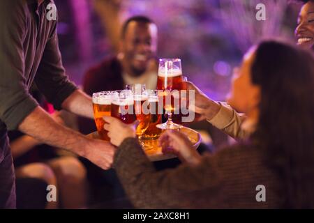 Man serving beer glasses to friends at party Stock Photo