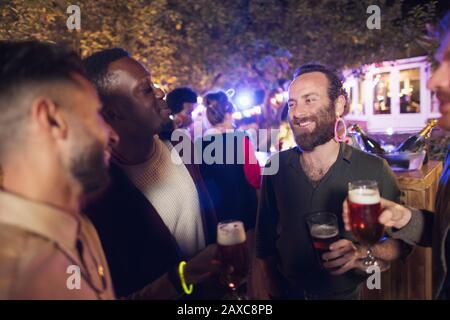 Happy male friends drinking beer at garden party Stock Photo